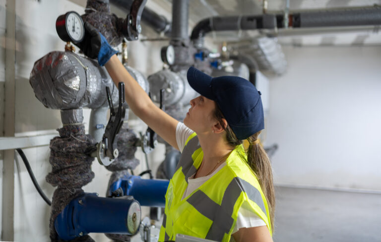 Female Engineer Checking Boiler System In A Basement